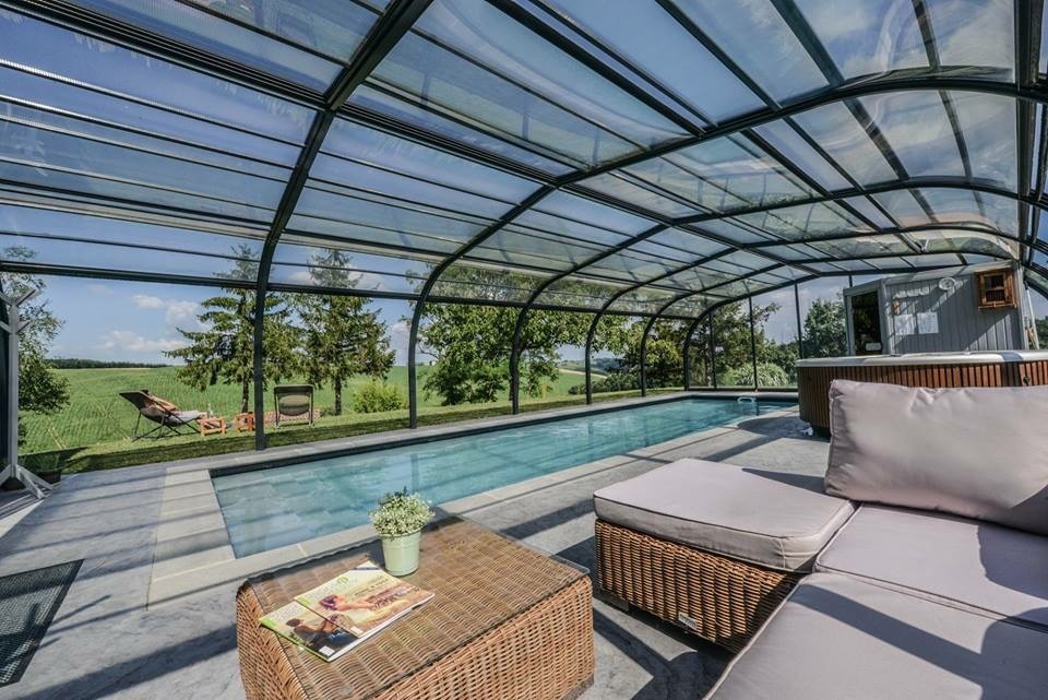 Piscine couverte ouverte sur le jardin, avec un espace salon